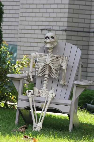 Skelett sitzt im Gartenstuhl — Stockfoto