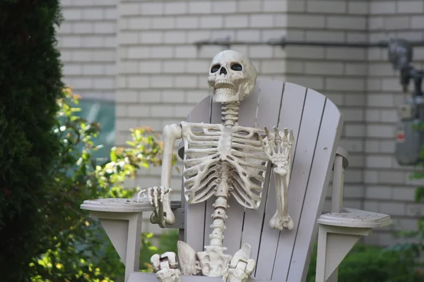 Esqueleto sentado en el patio silla — Foto de Stock