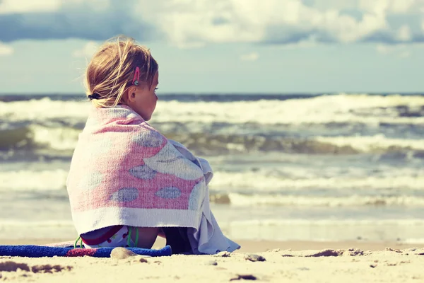 Liten flicka sitter på stranden — Stockfoto