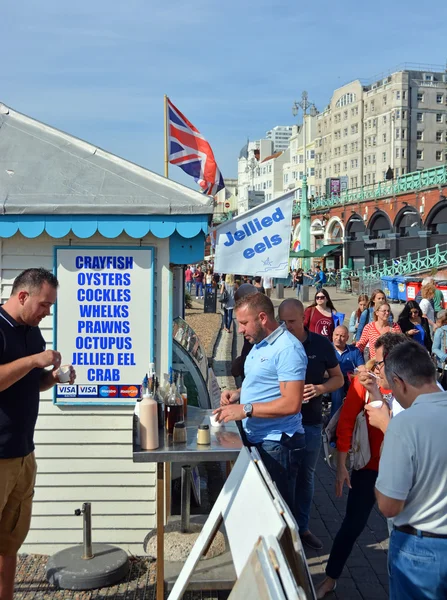 游客吃鳗鱼冻在布赖顿海滩上. — 图库照片