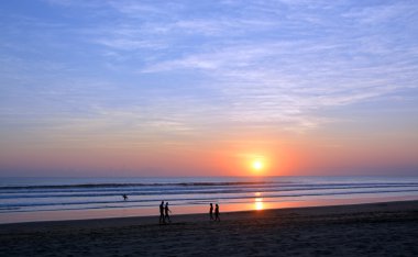 İnsanlar gün batımında Legian Beach, Bali üzerinde geziniyor