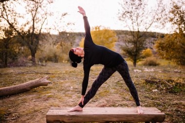 Yoga yapan ve park bankında uzanan bir kadın.