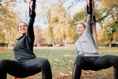 Kadınlar parkta trx ile antrenman yapıyor..