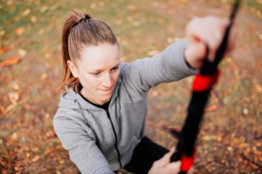 Kadınlar parkta trx ile antrenman yapıyor..