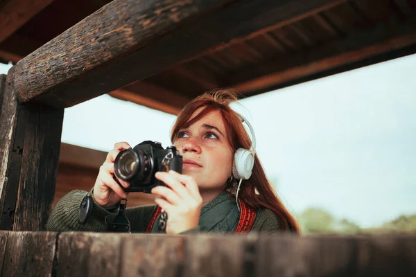 Mujer joven tomando fotos de cabaña de madera en el bosque — Foto de Stock