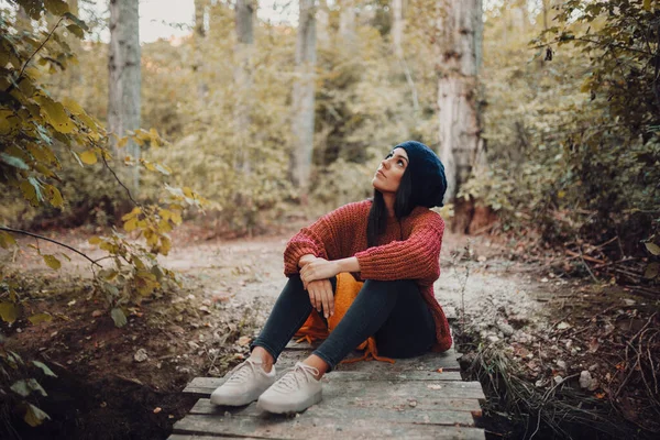 Giovane donna seduta su un piccolo ponte di legno nella foresta — Foto Stock