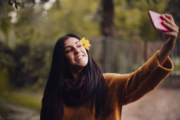 핸드폰으로 꽃을 머리에 꽂고 셀카를 하고 있는 여자 — 스톡 사진