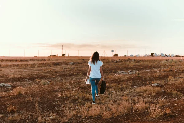 Genç bir kadın dizüstü bilgisayarıyla sahada yürüyor. — Stok fotoğraf