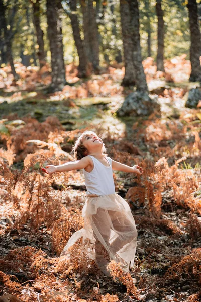 Pequena menina branca se agachando na floresta entre samambaias — Fotografia de Stock