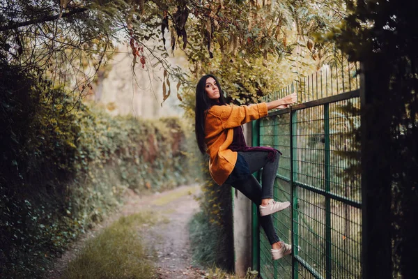 Mulher olhando através da cerca de metal na floresta — Fotografia de Stock