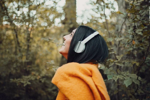Junge Frau hört Musik mit Kopfhörern im Wald — Stockfoto