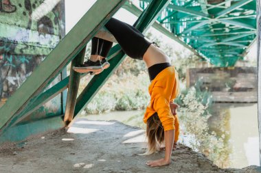 Kadın terk edilmiş bir köprüde akrobatlık yapıyor.