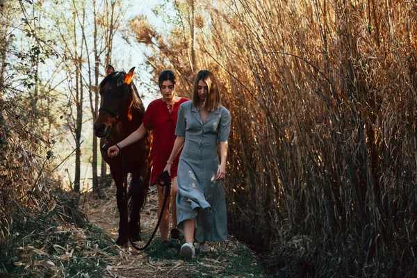 Two women friends chatting and taking a ride with their horse through the countryside