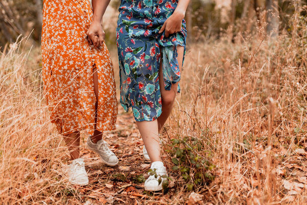 Two young lesbians walking in the woods wearing long dresses