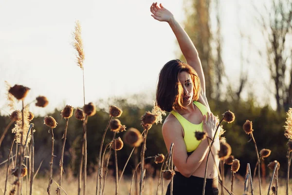 Brünette Frau in Sportbekleidung macht Stretchübung mit erhobenen Armen beim Training — Stockfoto