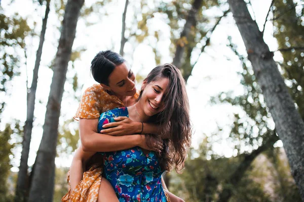 Femme piggyback heureux petite amie tout en appréciant sur la forêt — Photo