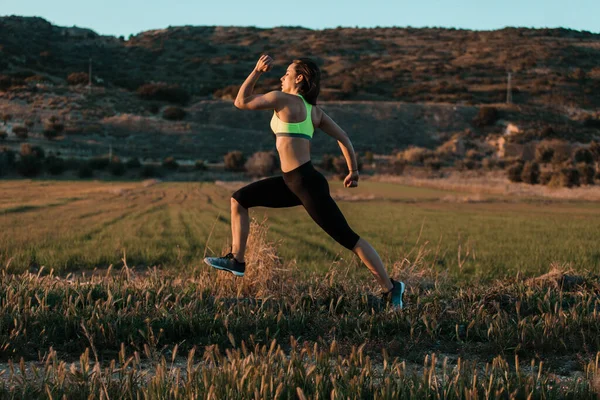 Una corredora corriendo por el prado de primavera. Entrenamiento en una naturaleza. — Foto de Stock