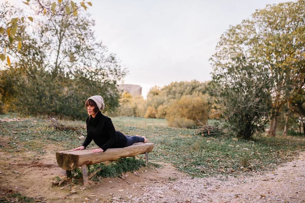 Kobieta ćwiczy jogę i rozciąga się na ławce w parku — Zdjęcie stockowe