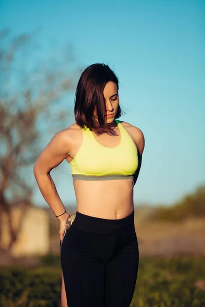 Corredor femenino estirando las piernas al aire libre en el campo antes del ejercicio — Foto de Stock