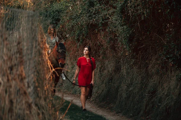 Duas mulheres amigas conversando e dando um passeio com seu cavalo pelo campo — Fotografia de Stock