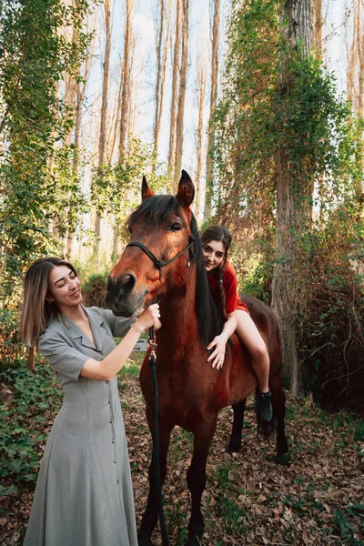 Duas mulheres amigas conversando e dando um passeio com seu cavalo pelo campo — Fotografia de Stock