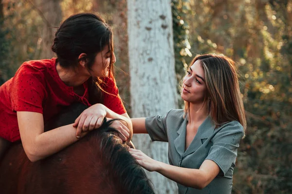 Dos amigas chateando y dando un paseo con su caballo por el campo —  Fotos de Stock