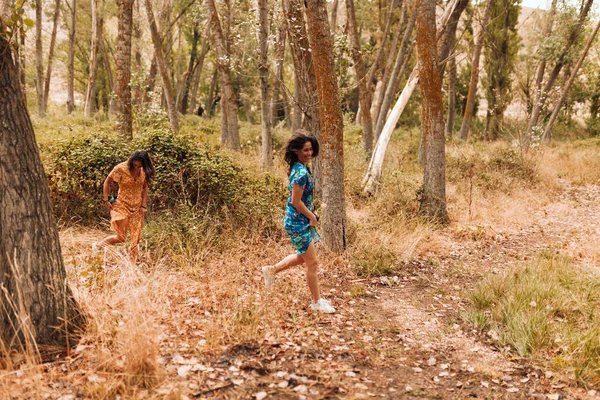 Two young lesbians walking in the woods wearing long dresses — Stock Photo, Image