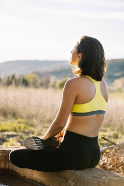 Genç ve güzel bir kadın parkta yoga egzersizleri yapıyor.