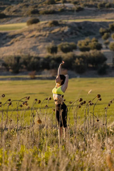 Жінка з спортивного одягу робить розтягування вправ з піднятими руками під час тренувань — стокове фото