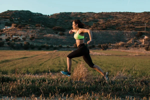 Una corredora corriendo por el prado de primavera. Entrenamiento en una naturaleza. — Foto de Stock