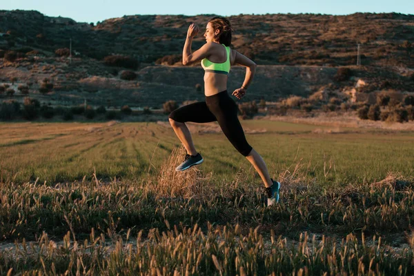 Una corredora corriendo por el prado de primavera. Entrenamiento en una naturaleza. — Foto de Stock