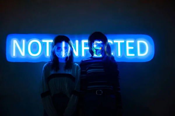 Two women by the wall with the not infected message projected onto their bodies — Stock Photo, Image
