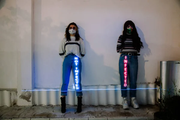 Två kvinnor vid väggen med infekterade och inte infekterade budskap projicerade på sina kroppar — Stockfoto