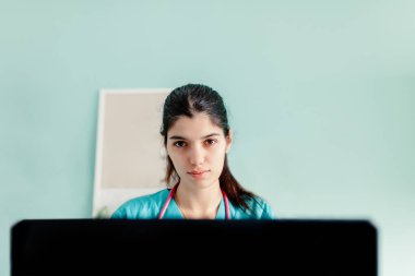 Klinikteki bilgisayarı kullanan kadın doktor.