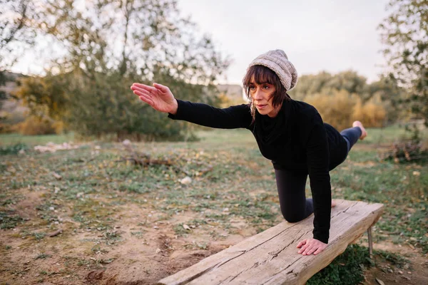 Femme pratiquant le yoga et s'étirant sur le banc du parc — Photo