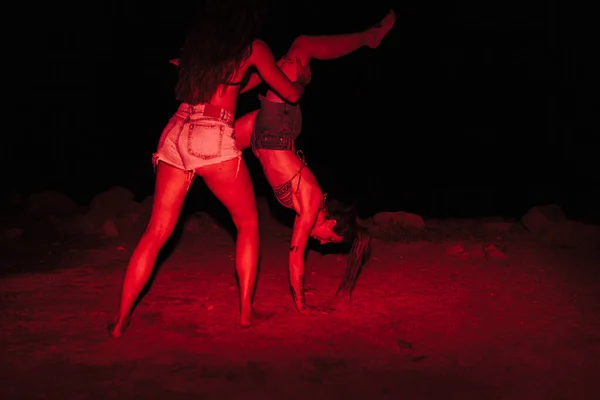 Grupo de jovens mulheres se divertindo em uma festa à beira do lago à noite com uma luz vermelha — Fotografia de Stock