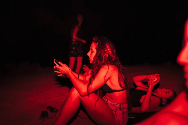 Grupo de jovens mulheres se divertindo em uma festa à beira do lago à noite com uma luz vermelha — Fotografia de Stock