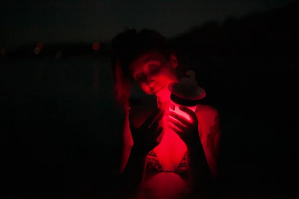Группа молодых женщин веселится на вечеринке у озера ночью с красным светом — стоковое фото