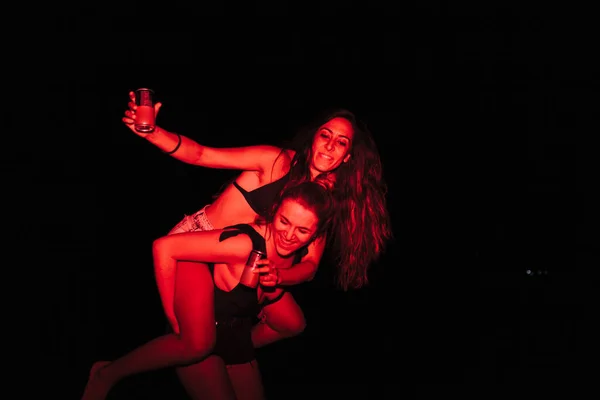 Group of young women having fun at a lakeside party at night with a red light — Stock Photo, Image