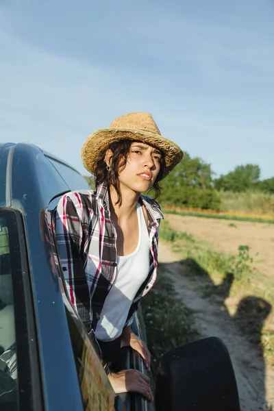 Junge Bäuerin im Lieferwagen schaut auf Getreidefeld — Stockfoto