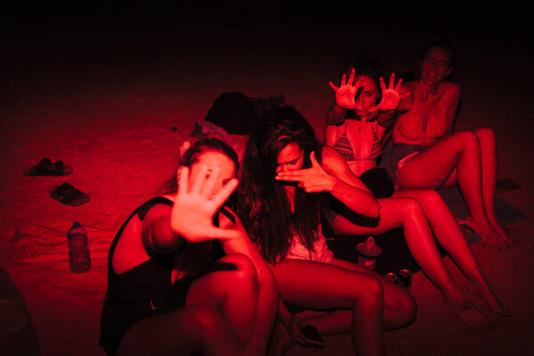 Group of young women having fun at a lakeside party at night with a red light