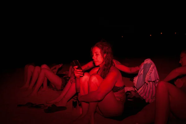 Grupo de jovens mulheres se divertindo em uma festa à beira do lago à noite com uma luz vermelha — Fotografia de Stock