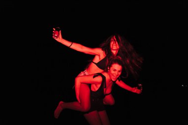 Bir grup genç kadın gece göldeki bir partide kırmızı ışıkta eğleniyorlar.