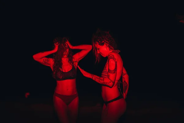 Группа молодых женщин веселится на вечеринке у озера ночью с красным светом — стоковое фото