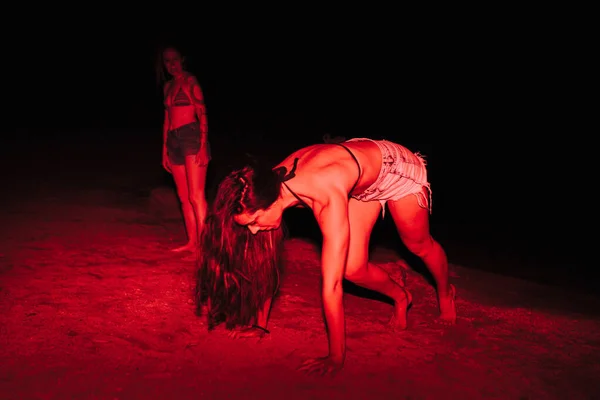 Group of young women having fun at a lakeside party at night with a red light — Stock Photo, Image