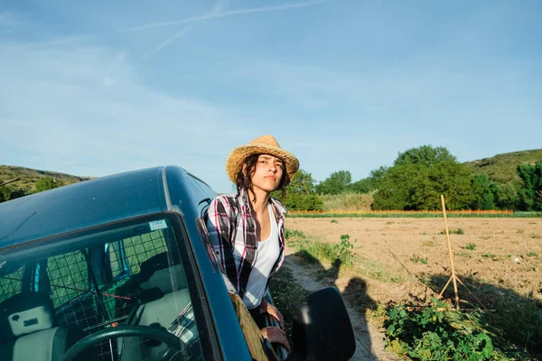 Jovem agricultor mulher em uma van olhando para o campo de cultivo — Fotografia de Stock