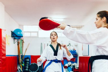 İki genç kadın bir eğitim merkezinde tekvando çalışıyor.