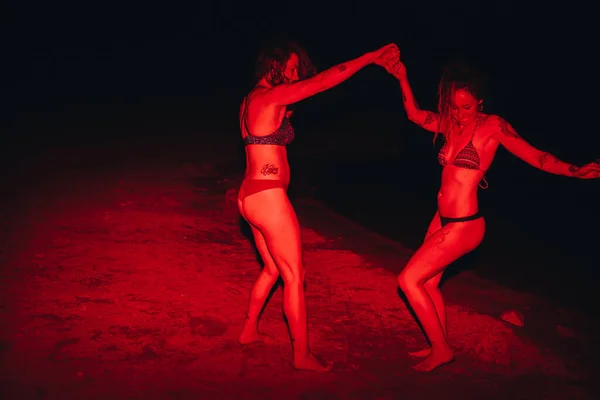 Group of young women having fun at a lakeside party at night with a red light — Stock Photo, Image