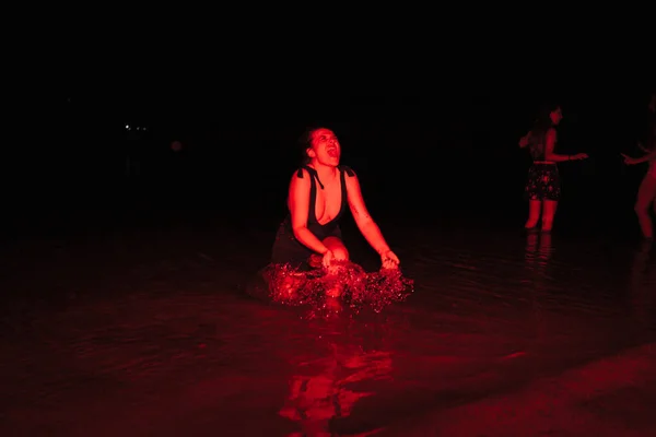 一群年轻女子在夜晚的湖边聚会上玩得很开心，还点着红灯 — 图库照片