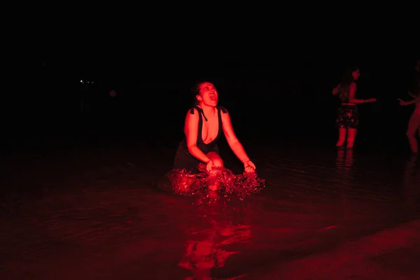 Grupo de jovens mulheres se divertindo em uma festa à beira do lago à noite com uma luz vermelha — Fotografia de Stock